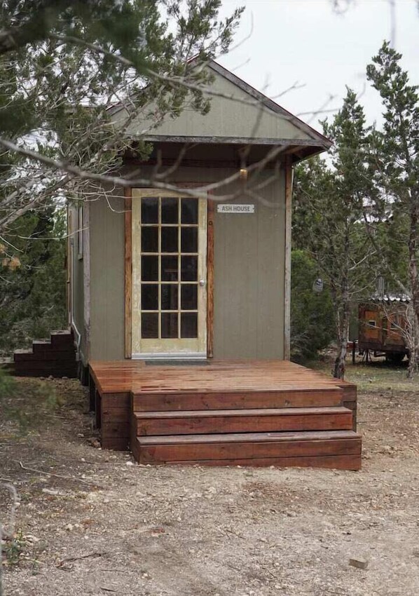 A small, single-story cabin with a wooden deck and a door.