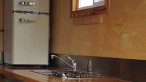 A kitchen with a vintage refrigerator, wooden countertop, and teal cabinets. - Pine Tiny House Rental (Bandera)