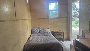 A small, single-bed room with wooden walls and a window. - Sage Brush Tiny House (Bandera)