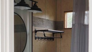 Ein Badezimmer mit einem weißen Waschbecken, einem schwarzen Schrank und einem Spiegel.