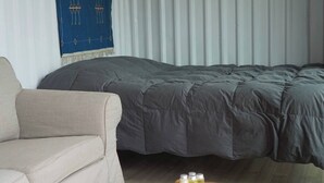 Ein Zimmer mit einem Bett, einer Schlafcouch und einem kleinen Tisch mit Flaschen.