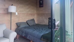 Een slaapkamer met een bed, een stoel, een lamp en een plafondventilator.