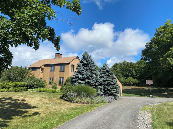A modern two-story house with a brick facade and large windows, surrounded by lush greenery and a well-maintained lawn. - A BEAUTIFUL 3 BEDROOM/2.5 BATH HILLTOP HOME IDEAL FOR GREAT ESCAPES,  (Chatham)