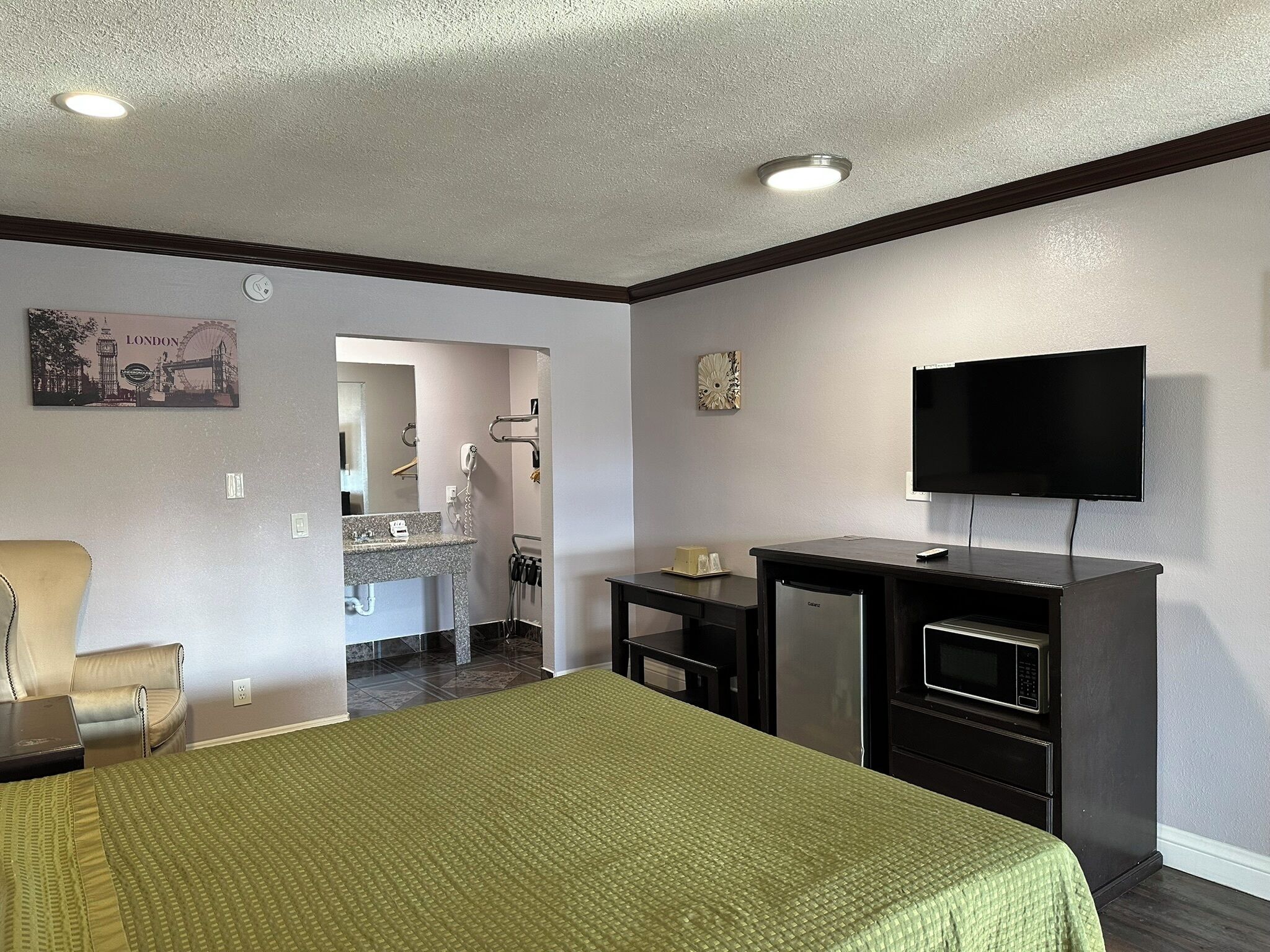 Una habitación de hotel con una cama, un escritorio con televisor, microondas y refrigerador pequeño.