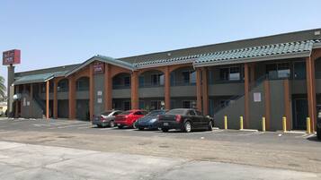 A multi-story building with a sign for Circle City Inn, featuring a parking lot with several cars, a staircase leading to the upper floors, and a flat roof.
