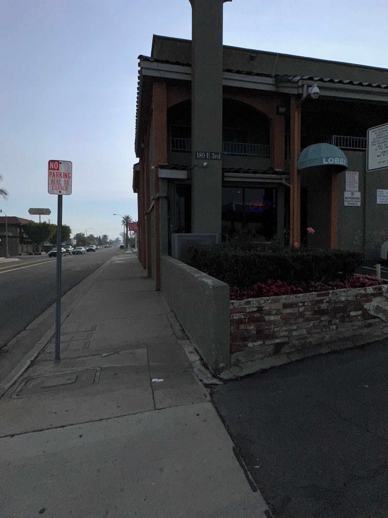 Un edificio con un cartel de 'No Parking', un cartel que indica 'Lobby' y una calle con coches estacionados.