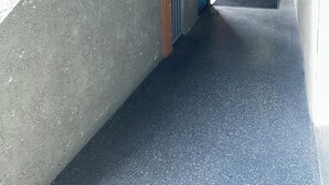 A covered outdoor corridor with a metal railing, a door leading to a lobby, and a sign indicating a no-smoking area. - Corona Inn (Corona)
