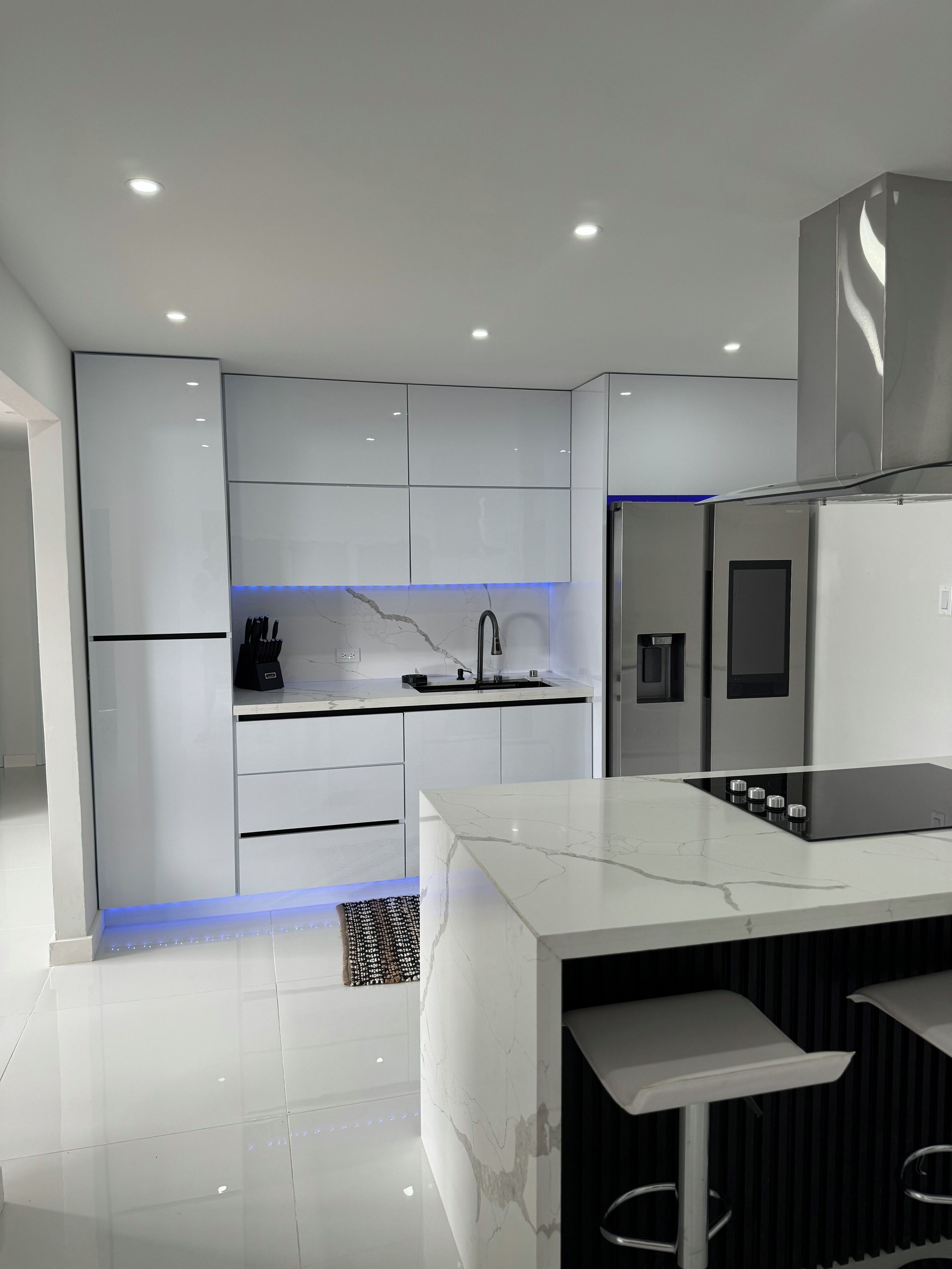 A modern kitchen with white cabinetry, a black countertop, and a built-in stove.