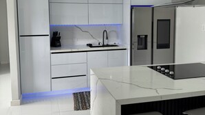 Uma cozinha moderna com armários brancos, bancada preta e fogão embutido.