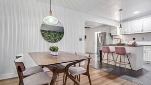 A modern kitchen with white cabinets, a stainless steel refrigerator, and a small island with bar stools. - Spacious 5-bedroom POOL House with WiFi and AC in charming Chula Vista (Chula Vista)