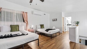 A modern hotel room with two single beds, a ceiling fan, an air conditioning unit, and a small kitchenette area. - Spacious 5-bedroom POOL House with WiFi and AC in charming Chula Vista (Chula Vista)