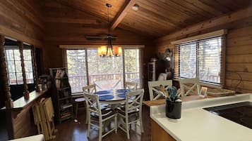 A wooden interior with a dining table, chairs, a kitchen island, and a chandelier.