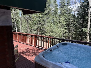 A hot tub on a wooden deck with a red railing, surrounded by trees. - Family Cabin in the Hills of Strawberry Valley (Duck Creek Village)