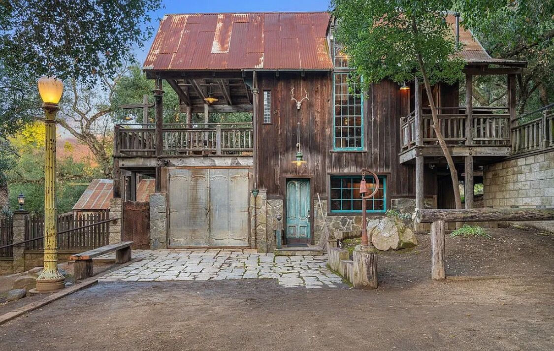 Ein rustikales Holzhaus mit Balkon, steinernen Eingang und Veranda.