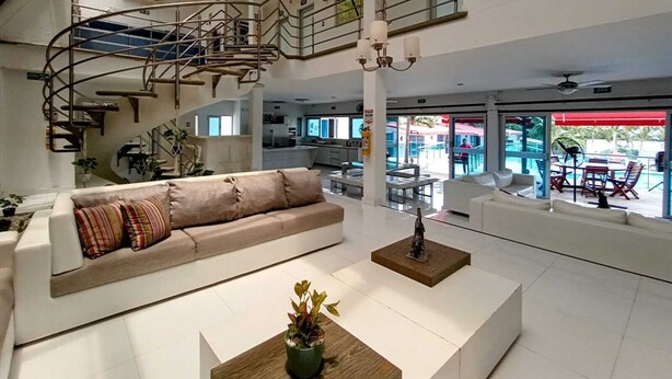 A spacious living area with a modern staircase, a sofa, a coffee table, and a view of the outdoor pool area. - HOTEL KAAMU TAGANGA (Santa Marta)