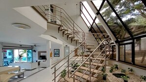 A modern interior with a spiral staircase, a living area with a sofa and TV, and a view through large windows. - HOTEL KAAMU TAGANGA (Santa Marta)