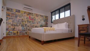A bedroom with a bed, wooden floor, and a wall covered with various posters.