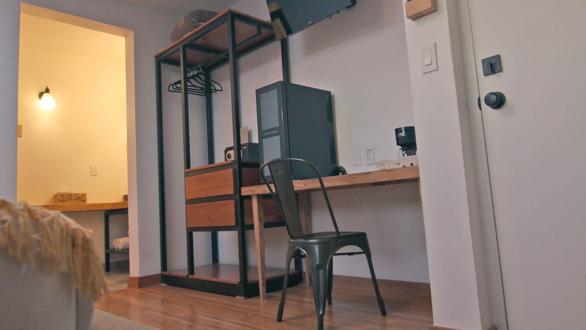 Una habitación pequeña y funcional con escritorio, silla y cama.