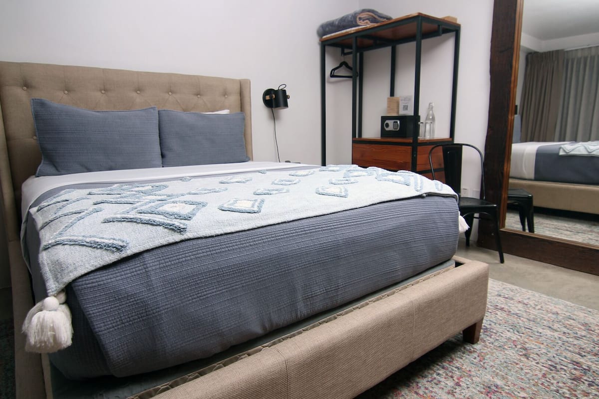 Une chambre à coucher avec un grand lit, une table de chevet, une chaise, une armoire et un miroir.