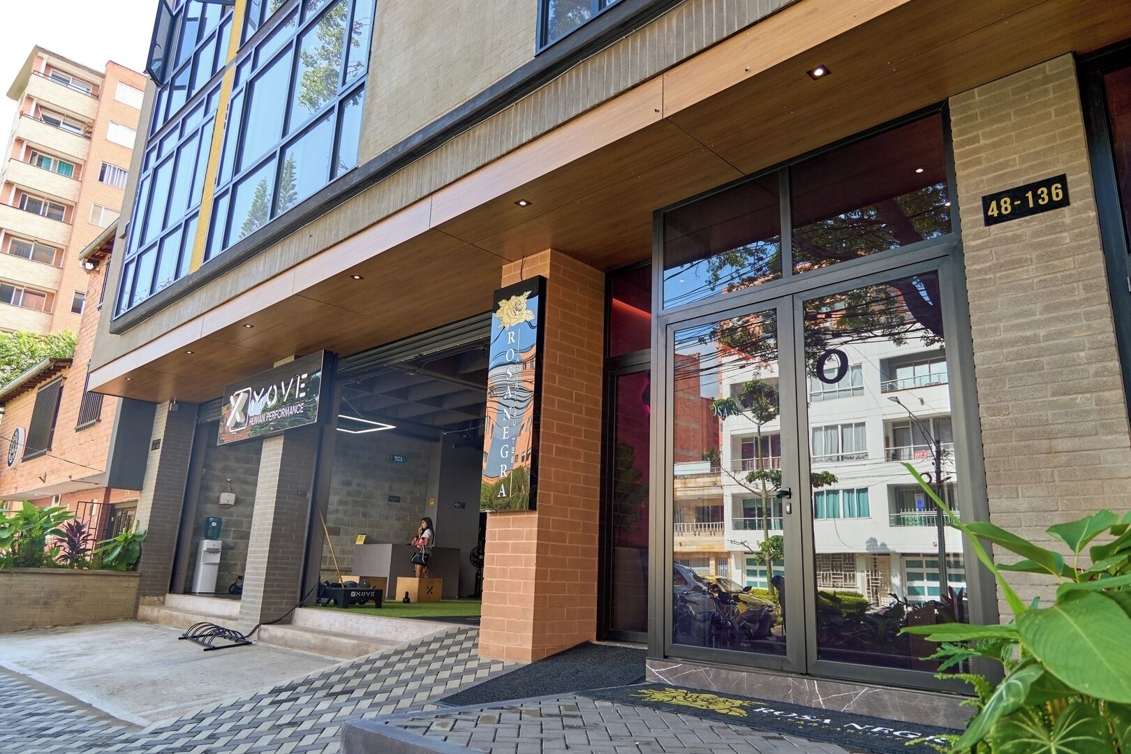 Un edificio moderno con un escaparate que dice "XMOVE HUMAN PERFORMANCE" y una amplia entrada de vidrio.