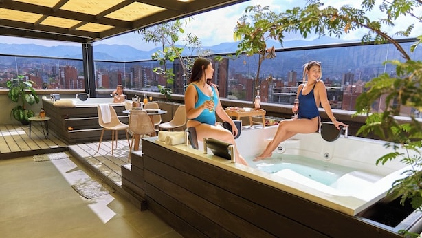 Terraza en la azotea con jacuzzi, zona de estar y vistas a la ciudad.