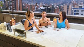 A hot tub with three people enjoying drinks, surrounded by a cityscape view. - Charming Aparta-suite Stadio Rosa Negra Retreat (Medellín)