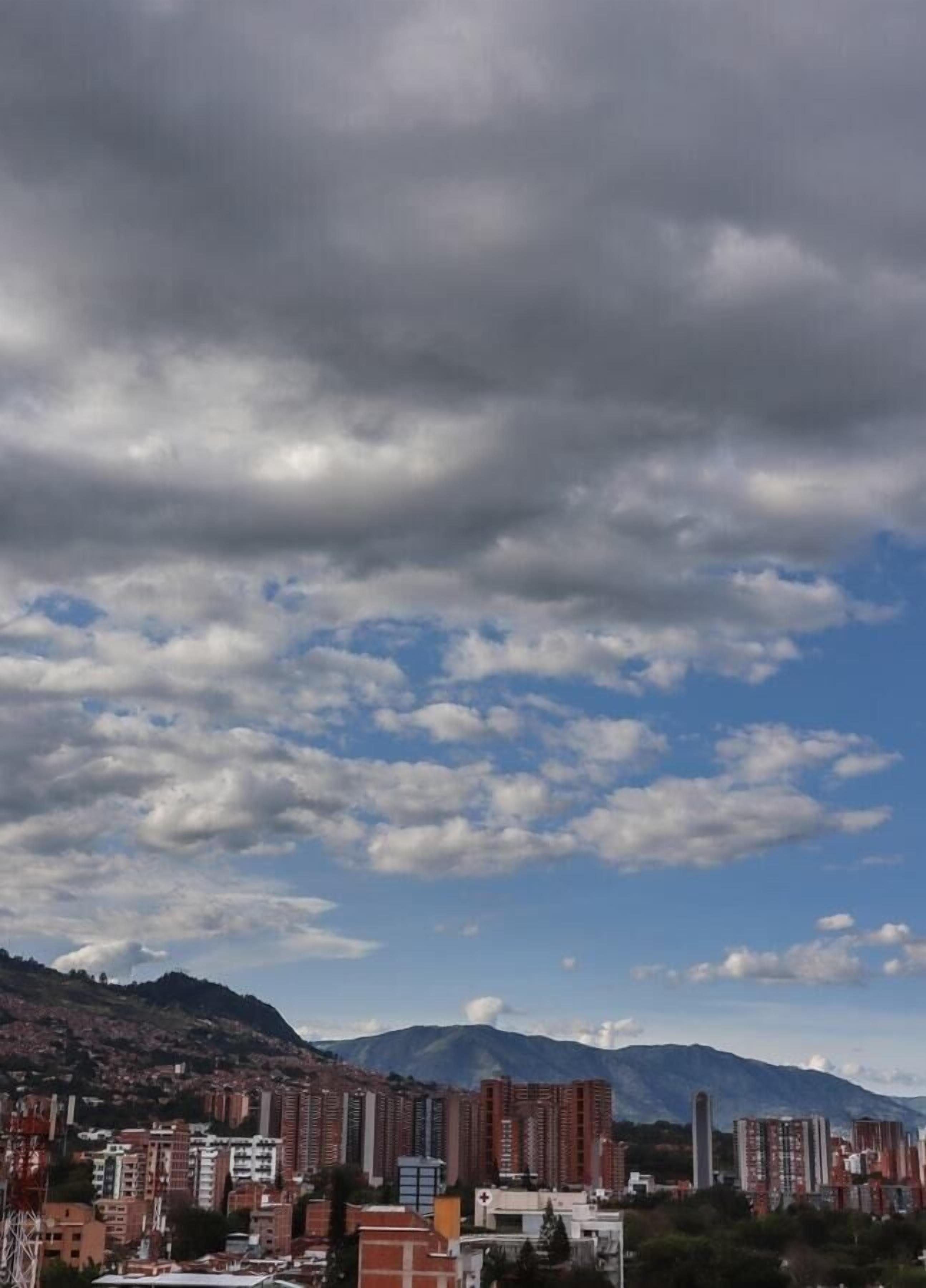 Un paisaje urbano con edificios altos y montañas al fondo.