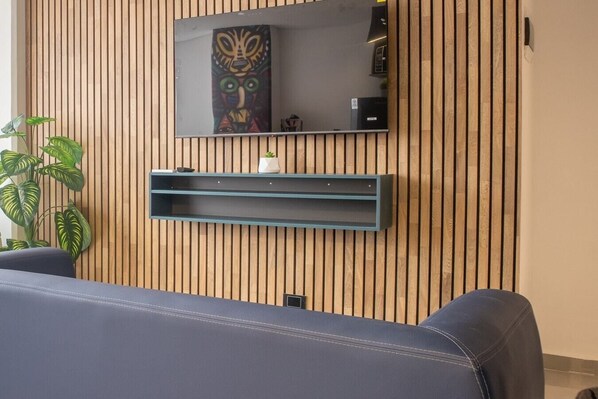 A modern room with a wooden slat wall, a mounted mirror, a small shelf, and a potted plant.
