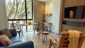 A modern living room with a sofa, a coffee table, a TV mounted on the wall, and a dining area with chairs and a small table. - Rosa Negra's Cozy Stadio Haven (Medellín)