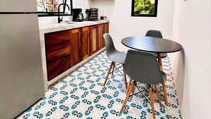 A compact kitchen with a refrigerator, wooden cabinets, a dining table with chairs, and a patterned floor. - Mountain View, Saltwater Pool, Kitchen, A/C, King Bed, Fast WiFi - “Montaña” (San Francisco)