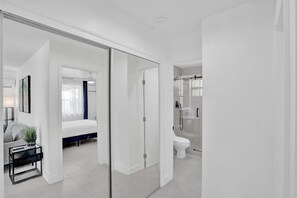 Una habitación de hotel moderna con una cama, una mesita de noche y una planta pequeña.