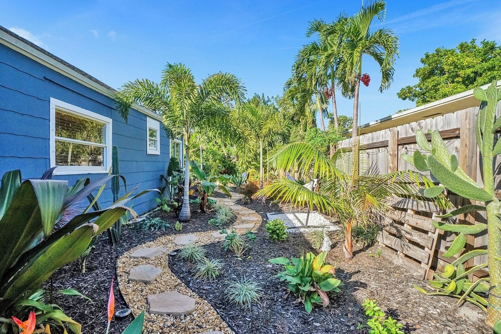 A garden with a variety of plants and a wooden fence.