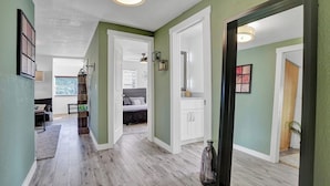 Un couloir doté d’un plancher en bois, de murs verts et de portes blanches donnant sur les chambres.