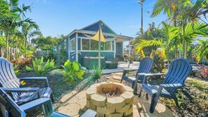 Une maison dotée d’un patio comprenant un foyer extérieur, des sièges de jardin et une végétation tropicale luxuriante.
