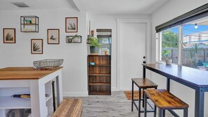 Une cuisine moderne avec un plan de travail en bois, des meubles blancs et une vue sur le jardin à travers une grande fenêtre.