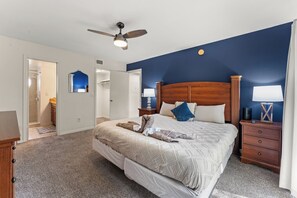 A bedroom with a large bed, wooden headboard, two bedside tables with lamps, a ceiling fan, and a walk-in closet. - 3-br Condo Near Disney Family-friendly Retreat (Kissimmee)