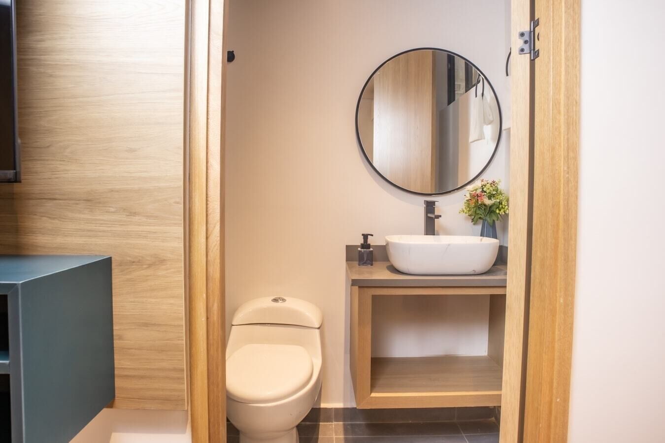 Un bagno moderno con il water, un lavandino con specchio e un mobile contenitore in legno.