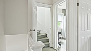 A staircase leading to a bathroom with white walls and a white door. - Spacious 4BR Getaway: Perfect for Family & Friends (Detroit)