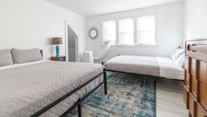 Un dormitorio con dos camas, un aparador, una lámpara y un espejo en la pared.