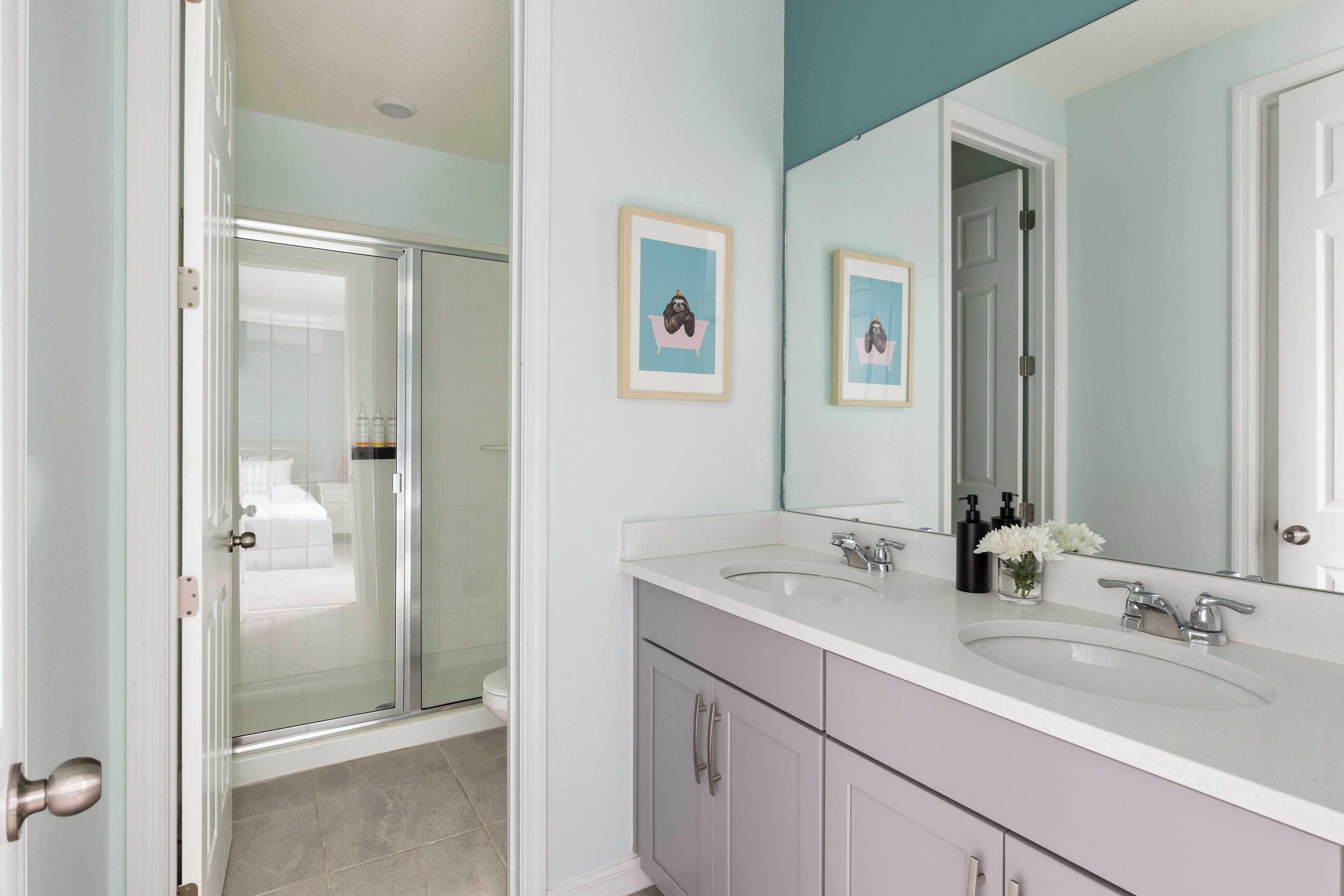 A bathroom with a double sink, a large mirror, and a glass shower enclosure.