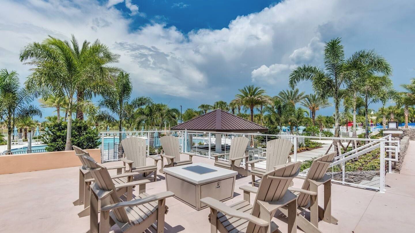 Un espace aménagé au bord de la piscine, avec des fauteuils Adirondack, une petite table et un gazebo.