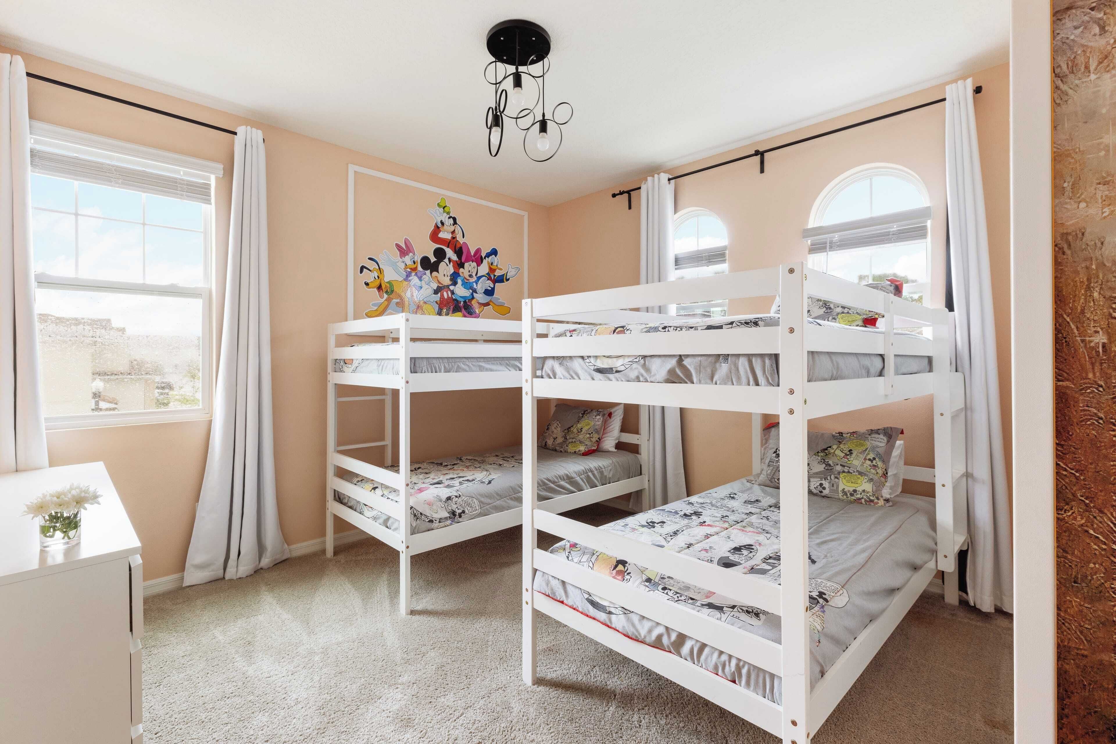 Een kamer met stapelbedden, een bureau en een raam met gordijnen.