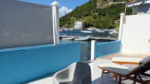 Un espace extérieur ensoleillé, aménagé avec une table, des chaises et un fauteuil de détente.