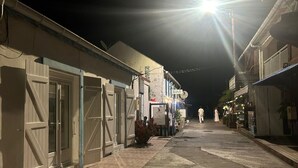Une rue étroite bordée d’immeubles, dont certains ont les volets fermés, et quelques enseignes indiquant la présence d’un bar.