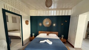 Une chambre à coucher comprenant un lit, des tables de chevet, un miroir, des éléments décoratifs sur les murs et un ventilateur de plafond.