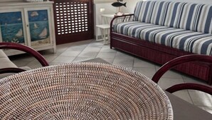 Un salon avec un canapé à rayures, une table en osier et un meuble orné de carreaux décoratifs.