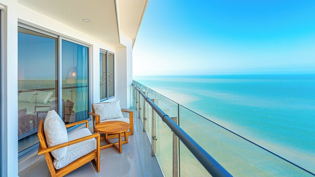 A balcony with a view of the ocean, furnished with wooden chairs and a table. - Cartagena Dreams (Cartagena)