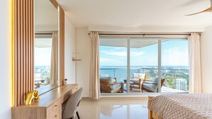 A modern hotel room with a large bed, a desk with a chair, a large mirror, and a balcony with a view of the city and the sea. - Cartagena Dreams (Cartagena)