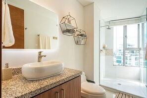 A modern bathroom with a granite countertop, a white sink, and a glass-enclosed shower. - Cartagena Dreams (Cartagena)