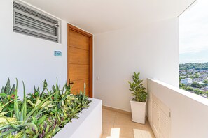 A balcony with a view of a cityscape, a wooden door, and potted plants. - Cartagena Dreams (Cartagena)